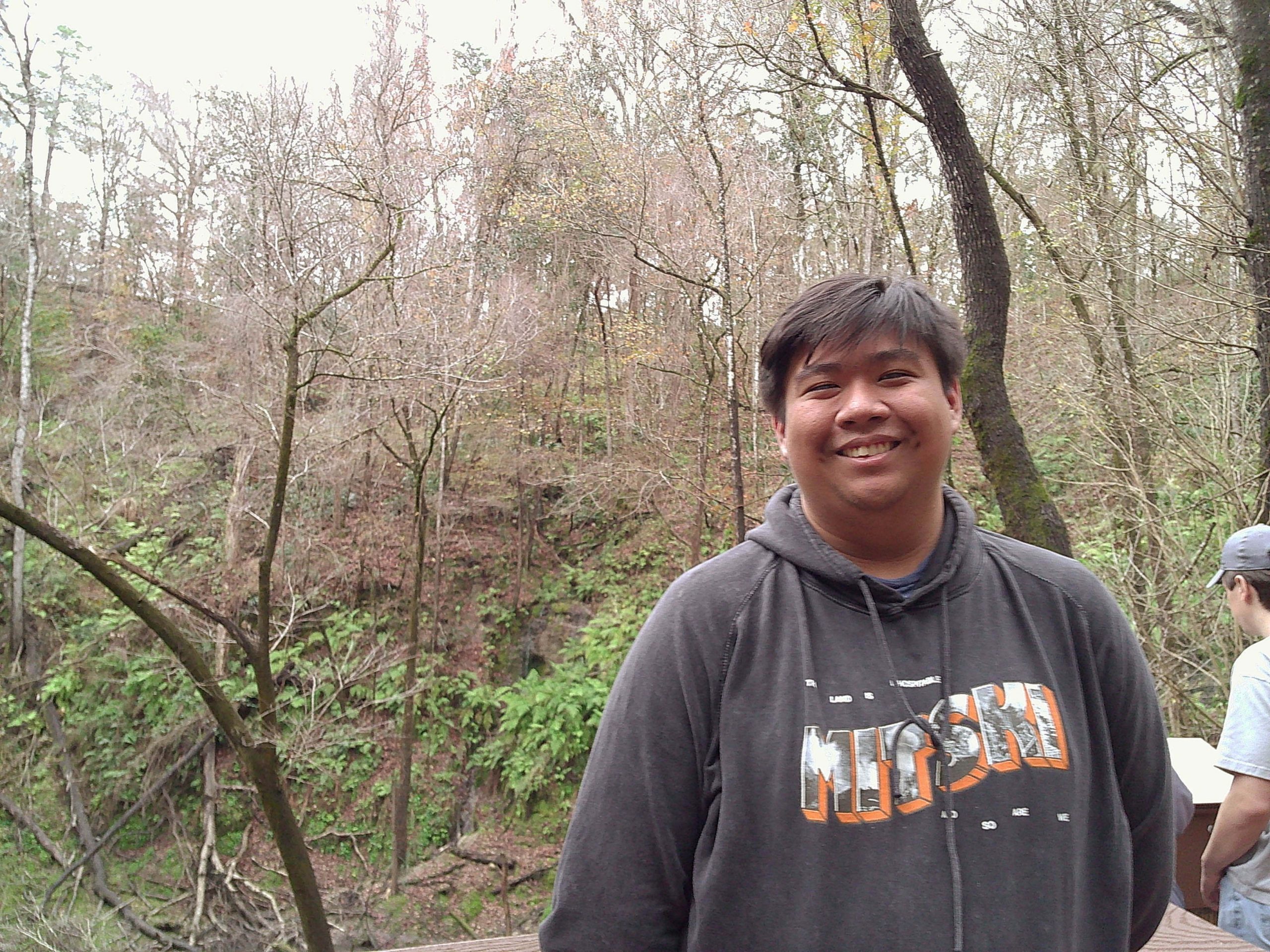 Data Integration Intern Gregory Nobleza stands outside near trees. 