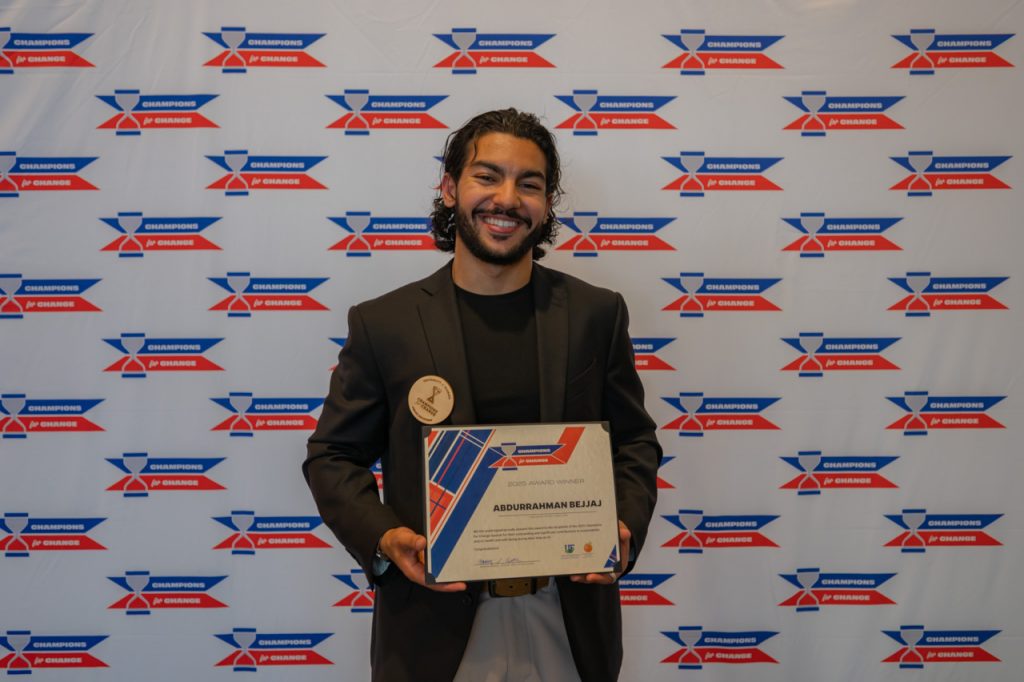 2025 Champions for Change Award Recipient, Abdu Bejjaj pose with their award certificate.
