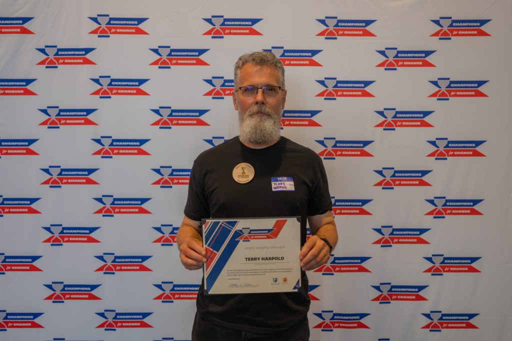 2025 Champions for Change Award Recipient, Terry Harpold, pose with their award certificate.