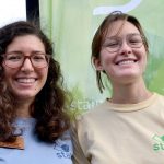 Sustainable UF Interns smile at the camera in front of Sustainable UF's flag