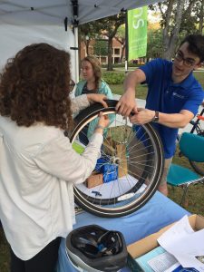 Two students are working together to place new tires on a bicycle during the Sustainable Transportation Fair