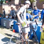 Student with bicycle stops at Sustainable Transportation Fair tables