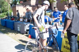 Student with bicycle stops at Sustainable Transportation Fair tables