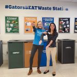 Two student volunteers doing the Gator Chomp infront of the GatorsBeatWaste Station