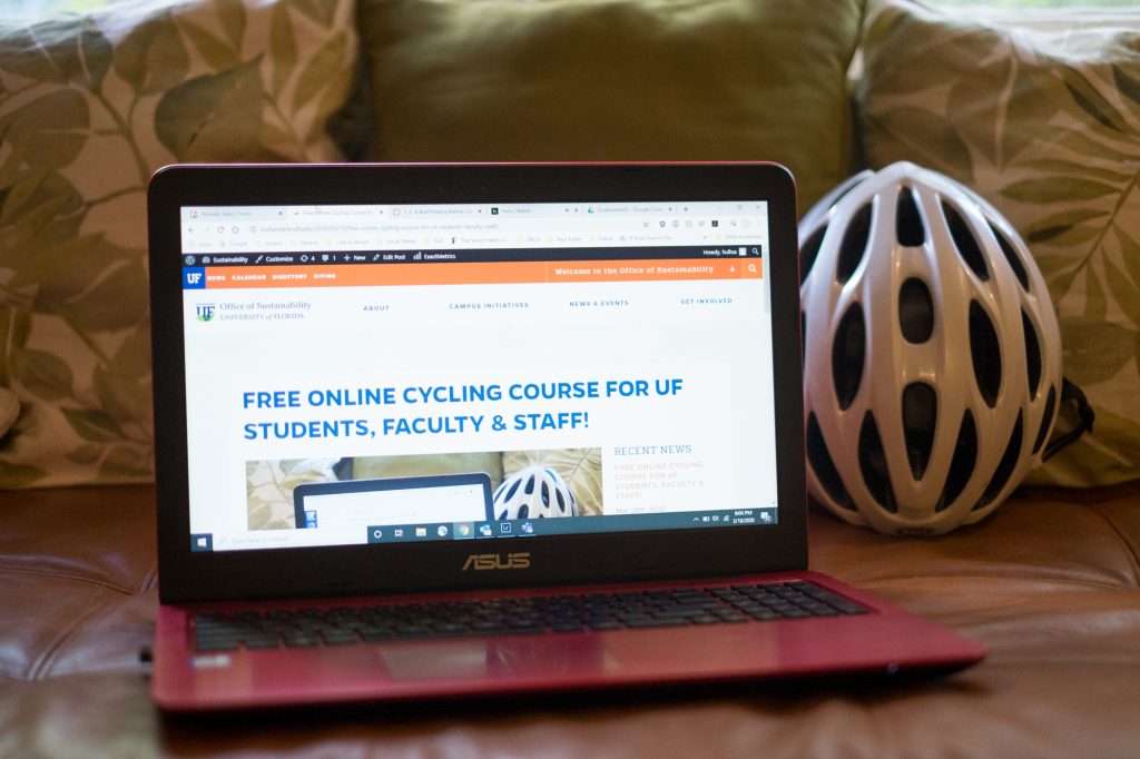 Laptop showing an online cycling course on a couch next to a helmet