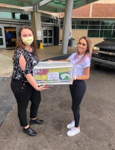 Two UF students carrying a box of food donations for essential staff members in front of Shands Emergency Room