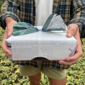 Student holding present that is wrapped in newspaper to reduce waste