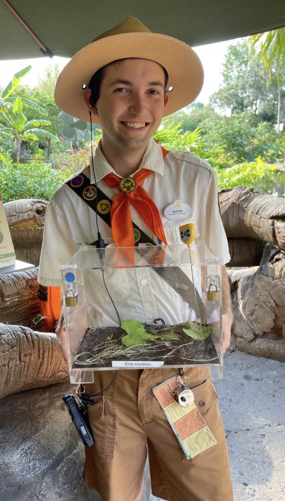 David Flores working in his internship at Disney, holding a reptile in a natural area. 